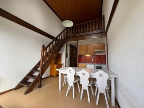 Eine kleine Küche mit Holdekor, einer weißen Arbeitsfläche und einem Essbereich mit einer Holztreppe.