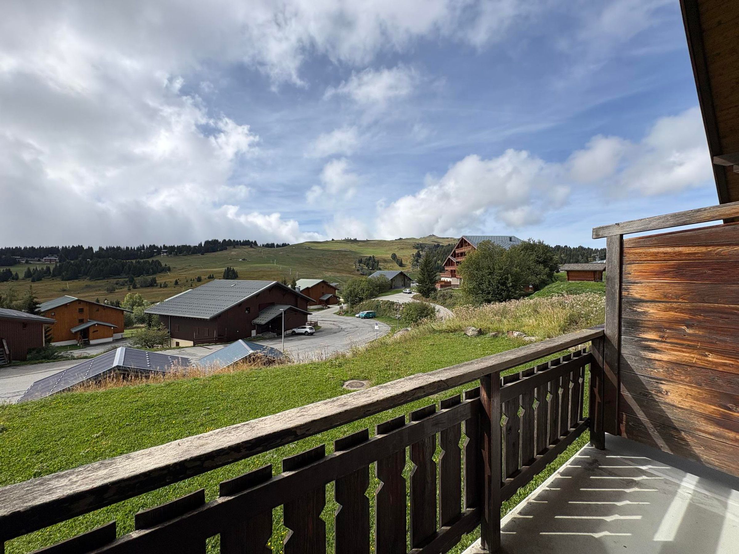 A balcony with a view of a rural landscape, including houses and a hill.