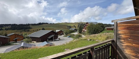 A balcony with a view of a rural landscape, including houses and a hill.