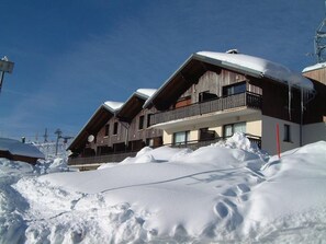 Un bâtiment de style chalet, doté d’un toit en pente et d’une façade en bois, entouré de neige.