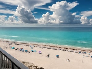 Une plage avec des parasols et des chaises longues, un ciel dégagé et l’océan.