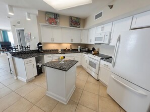 A modern kitchen with white cabinets, a granite countertop, a built-in oven, and a refrigerator. - 14th Floor End Unit w/ Wraparound Balcony (Orange Beach)
