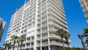 A multi-story hotel with balconies, palm trees, and a clear blue sky. - 14th Floor End Unit w/ Wraparound Balcony (Orange Beach)