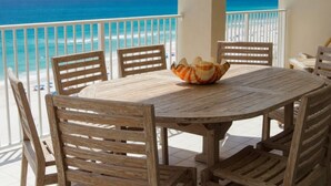 A wooden table with chairs on a balcony overlooking a beach. - 14th Floor End Unit w/ Wraparound Balcony (Orange Beach)