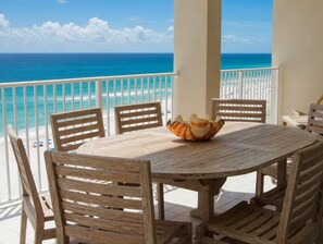 A wooden table with chairs on a balcony overlooking a beach. - 14th Floor End Unit w/ Wraparound Balcony (Orange Beach)