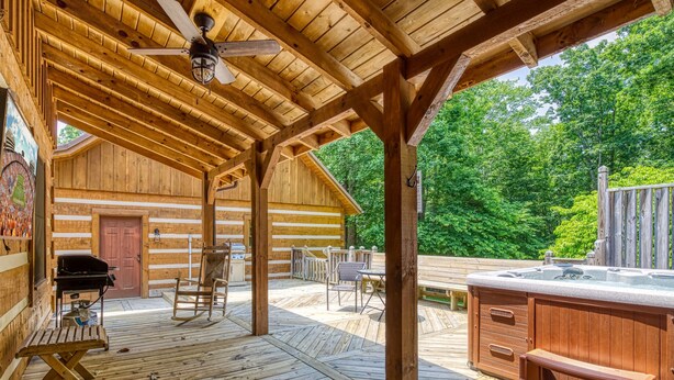 Een houten terras met een barbecue, zitplaatsen en een jacuzzi.