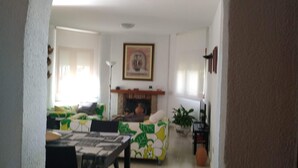 Ein Wohnzimmer mit einer Couch, einem Couchtisch und einem Kamin. An der Wand hängt ein gerahmtes Bild und auf dem Boden steht eine Pflanze.