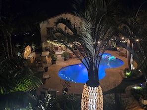 Zona de piscina con piscina circular, rodeada de plantas en macetas y mobiliario exterior.