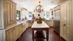 A spacious kitchen with light-colored cabinets, a central island, and a stainless steel refrigerator.