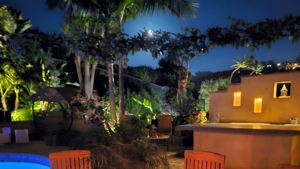 A poolside area with wooden chairs, a fire pit, and a small pool.