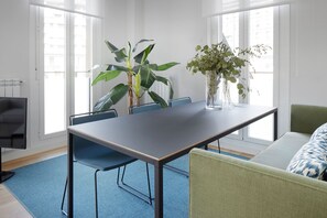 Et moderne værelse med et stort bord, stole, en sofa og to potteplanter.