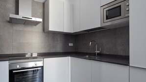 A modern kitchen with white cabinets, a stainless steel oven, a microwave, and a black countertop. - Muinoa 5 by FeelFree Rentals (San Sebastián)