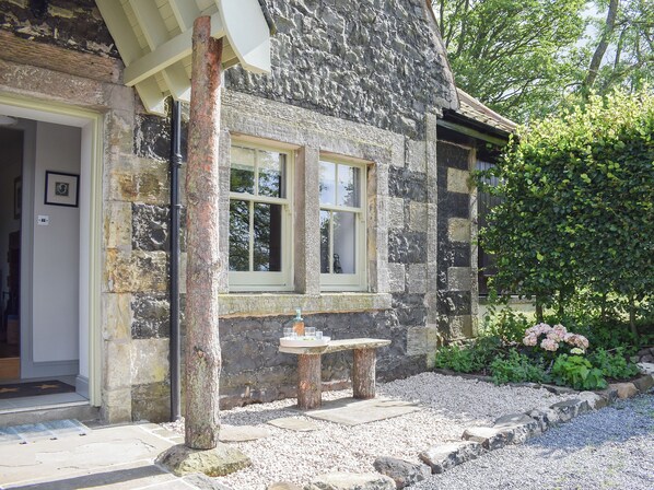 A stone building with a door, windows, and a small table with glasses.