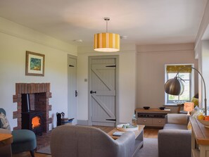 A living room with a brick fireplace, a staircase, a dining area, and a window with a view.