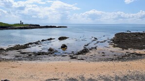 A coastal landscape with a lighthouse, rocky shoreline, and calm sea. - The Lodge @ East Neuk Orchards (Pittenweem, near Anstruther)