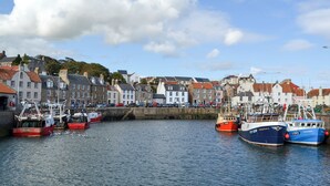 A harbor with boats docked, buildings with varied architecture, and a clear sky. - The Lodge @ East Neuk Orchards (Pittenweem, near Anstruther)