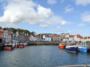 A harbor with boats docked, buildings with varied architecture, and a clear sky.