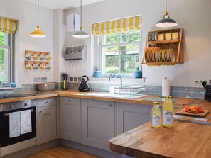A modern kitchen with a wooden countertop, a kettle, and a sink.