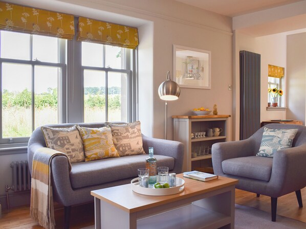A living room with a sofa, armchair, and a coffee table with a tray of glasses and a book.
