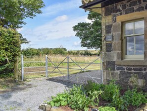 A stone building with a metal gate, a window, and a sign reading 'The Lodge.'