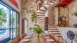 Enjoy meals in this stylish dining area with a long table, stone wall, and unique spiral staircase.