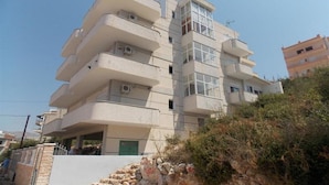 Un edificio de varios pisos con balcones, una puerta verde y un cielo despejado.