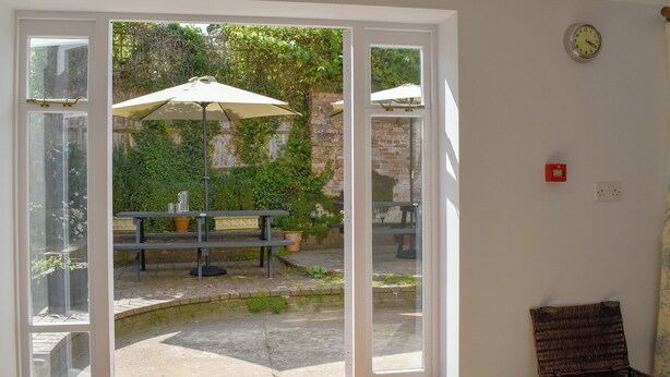A room with a sliding glass door leading to an outdoor patio area with a table and umbrella. - 5 bedroom accommodation in Wimborne (Wimborne)