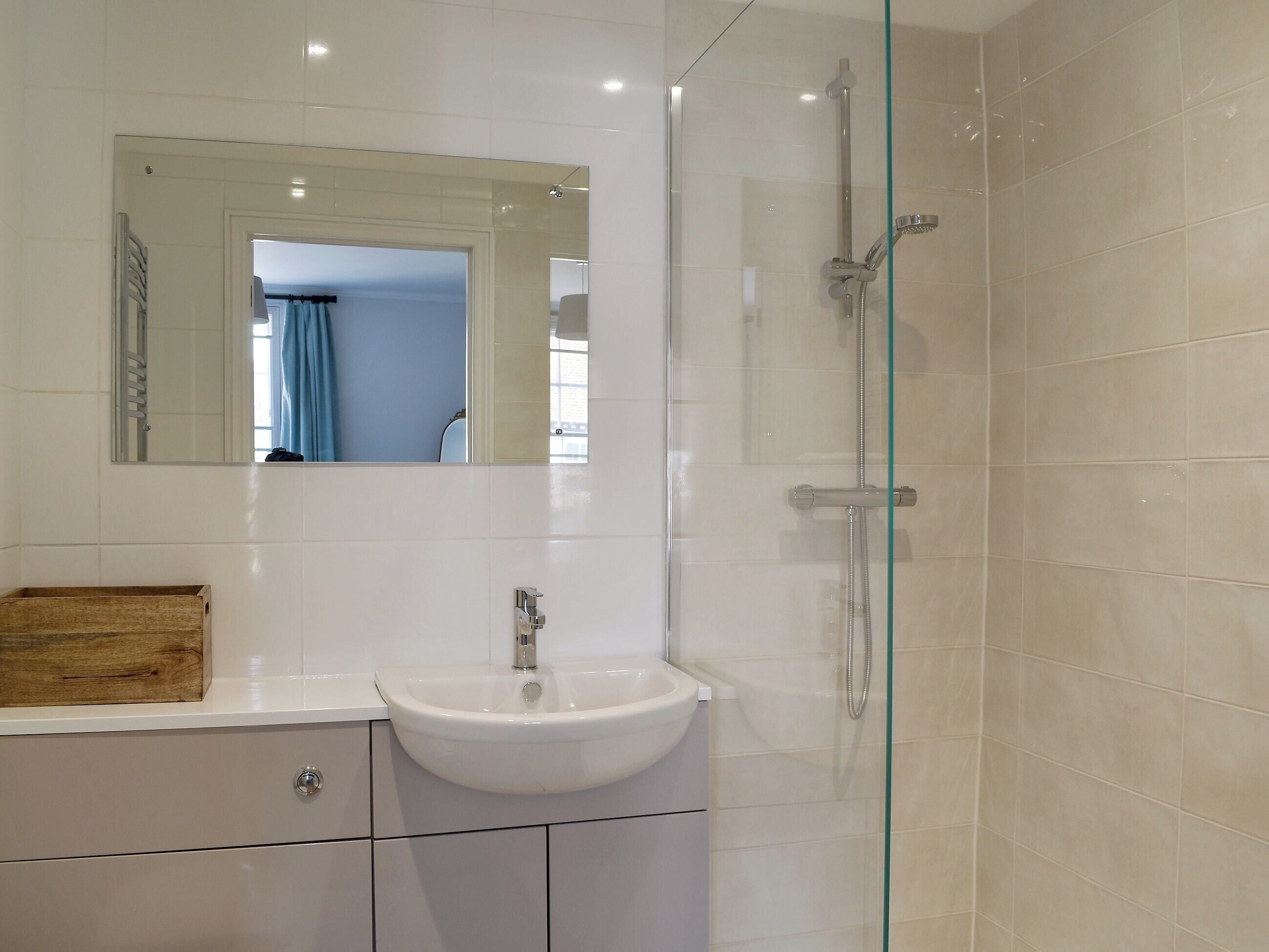A bathroom with a white sink, mirror, and glass shower enclosure.