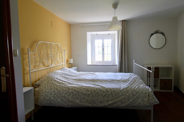 Une chambre à coucher avec un lit, une fenêtre, un miroir et un radiateur blanc.