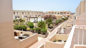 Un hotel con varios balcones, piscina y un jardín con diversas plantas y flores.