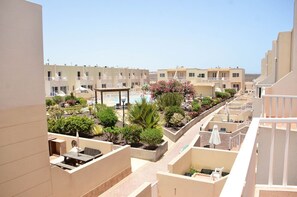 A hotel with multiple balconies, a pool, and a garden area with various plants and flowers. - 'Casa Caleta' Beautiful 3-Bed Home, fabulous outdoor space, Beach 5 mins walk! (Costa Caleta)