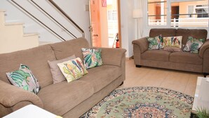 Una sala de estar con dos sofás, un tapete estampado y una escalera.