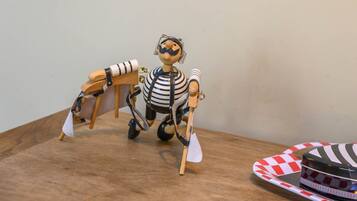 Een houten speelfiguur met een geruit shirt en een schep, op een houten ondergrond.