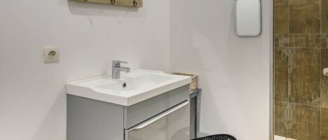 A bathroom with a white sink, a wooden-framed mirror, and a small mirror on the wall.