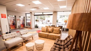 A modern lobby with seating areas, a reception desk, and a view of the street outside. - Hotel 10 Balsas (Balsas)