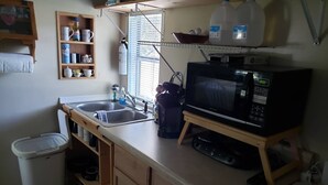 A compact kitchen with a microwave, sink, and wooden cabinets.