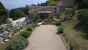 A house with a gravel driveway, surrounded by greenery and a hillside. - Completely renovated Mas Provencal (Manosque)