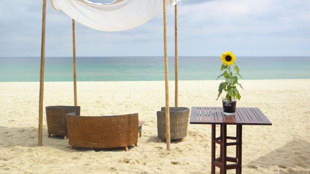 A beach setting with a canopy, wicker furniture, a table with a potted plant, and a view of the ocean. - Apartment Cabrera Burriac (Cabrera de Mar)
