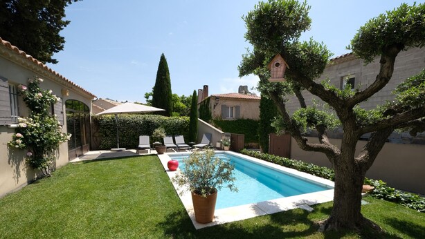 A backyard with a swimming pool, a tree, and a small garden. - Vacation rental house with pool AUREILLE LS1-277 (Aureille)