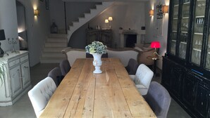 A dining area with a wooden table, six chairs, a vase with flowers, a staircase, and a cabinet with glass doors. - Vacation rental house with pool AUREILLE LS1-277 (Aureille)
