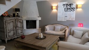 A living room with a fireplace, a sofa, a coffee table, and a wall-mounted light fixture. - Vacation rental house with pool AUREILLE LS1-277 (Aureille)