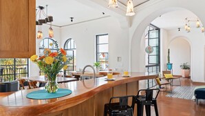 Una cucina moderna con bancone in legno, ampie finestre e lampade a sospensione.