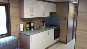 Cocina compacta con armarios blancos, un lavamanos, una estufa y un ventanal.