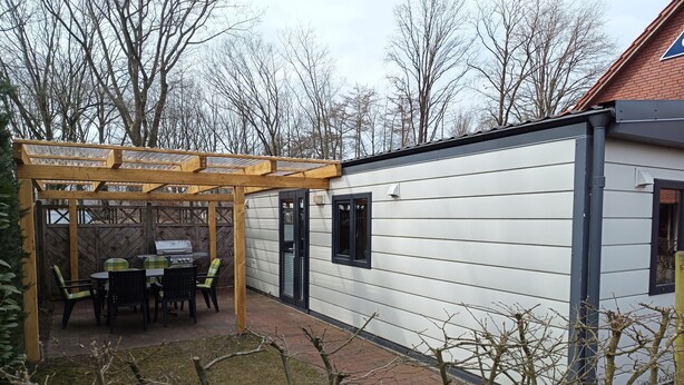 Un área de patio con una pérgola, mobiliario exterior y una parrilla.