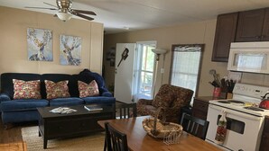Una sala de estar con un sofá azul, una mesa de comedor y una zona de cocina con estufa y microondas.