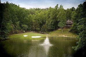 Ein Golfplatz mit Teich, Springbrunnen und einem Haus im Hintergrund.
