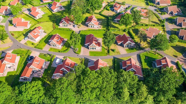 Vue aérienne d’un quartier résidentiel avec des maisons, des rues et des espaces verts.