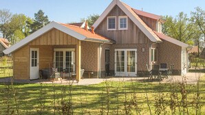 Une maison à deux étages, avec une façade en briques, un porche en bois et une terrasse couverte.