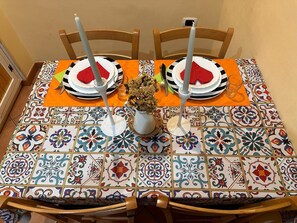 A dining table with a colorful tile pattern, two chairs, a vase with flowers, and plates with napkins. - "Ricomincio Da Qui" a few steps from the historic center (Napoli)
