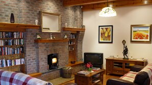 A cozy living room with a brick fireplace, bookshelves, a television, and comfortable seating. - Large Luxury House in Excellent Location. Ideal for families  (Killarney)